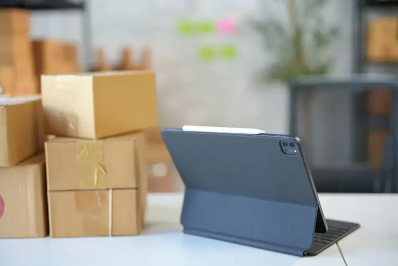 Warehouse manager using a B2B ordering portal on a tablet beside stacked pallets
