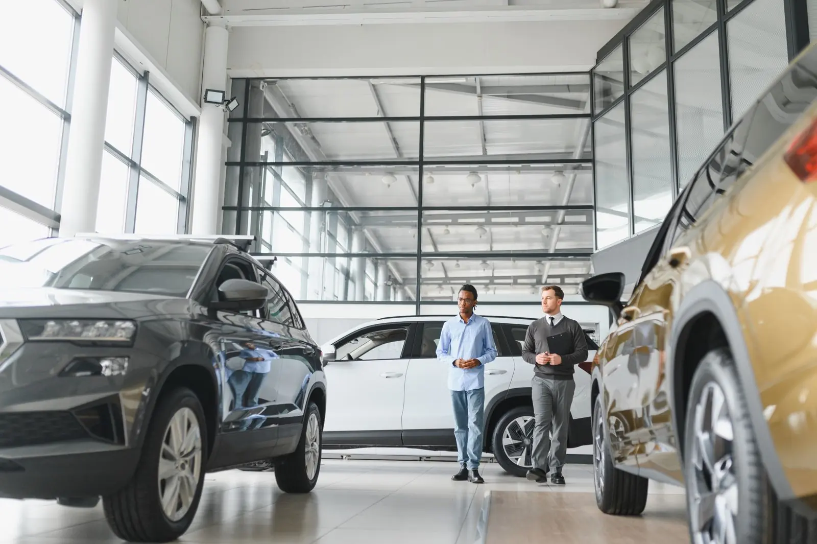Salesperson and customer looking at a vehicle listing on a tablet on a car dealer forecourt