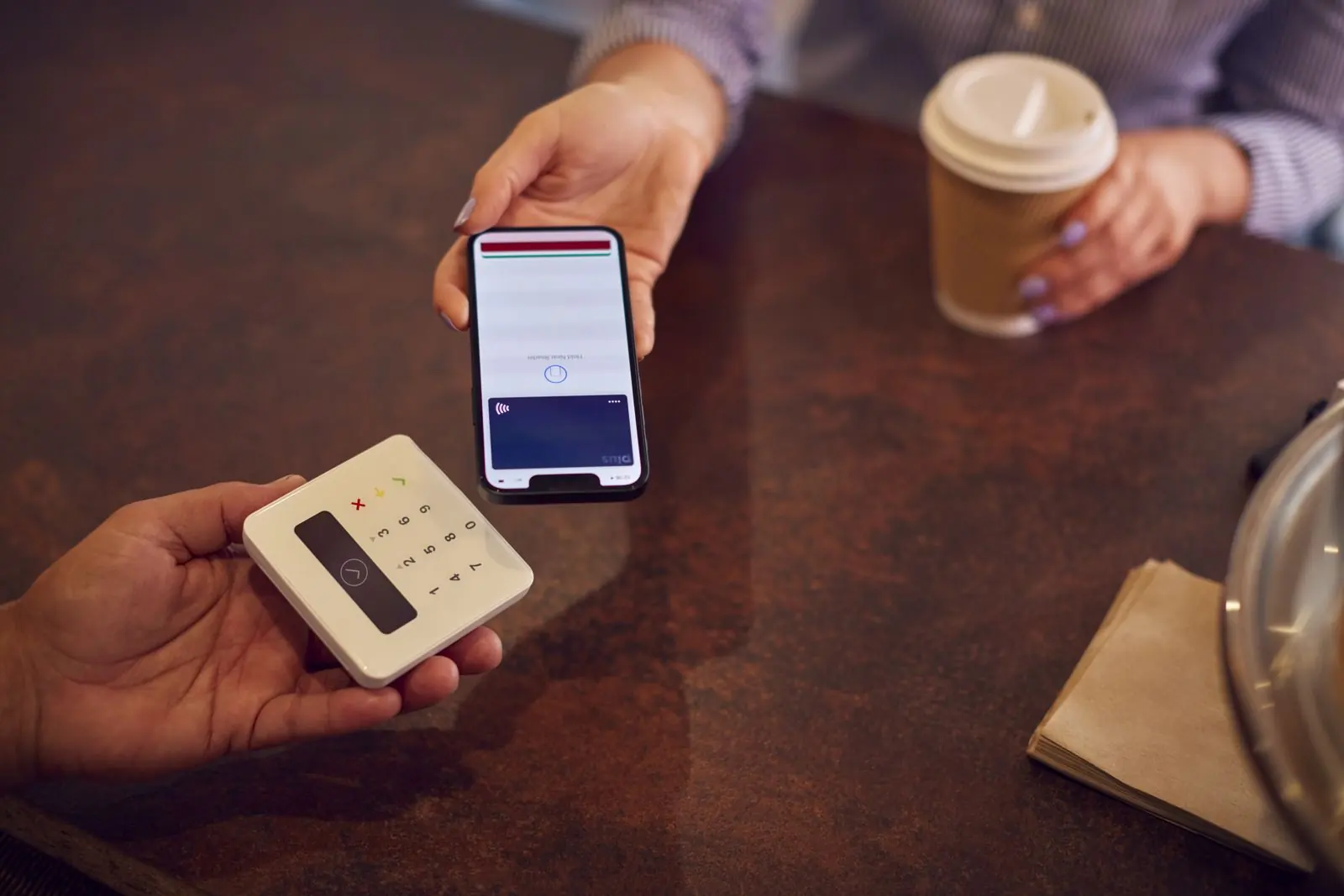 Customer scanning a digital loyalty app on their phone at a cafe counter