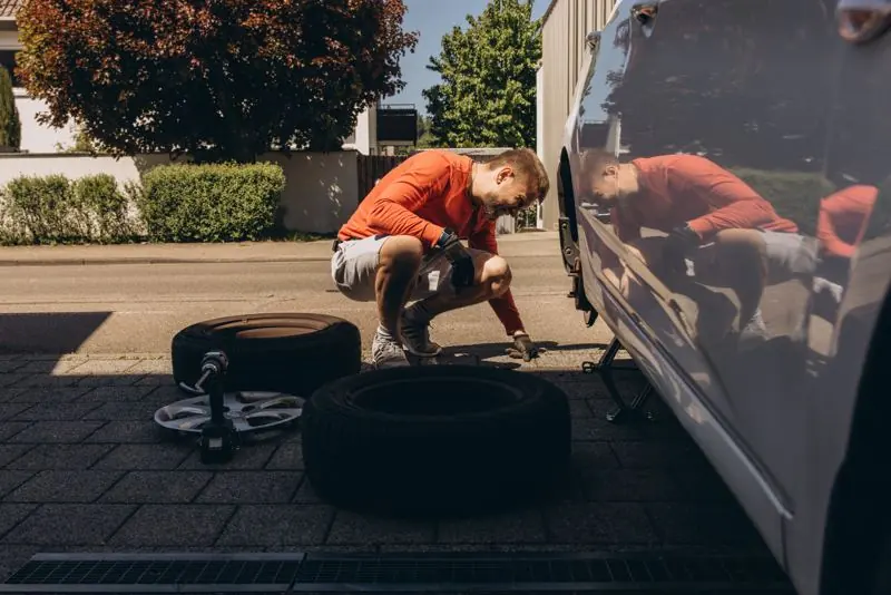 Tyre fitter next to a van holding a phone that shows a postcode coverage checker and call button
