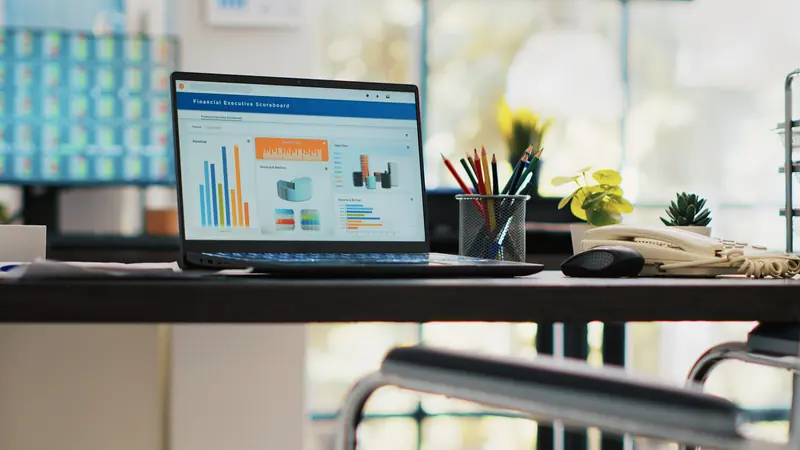Laptop on an office desk showing a website dashboard with charts
